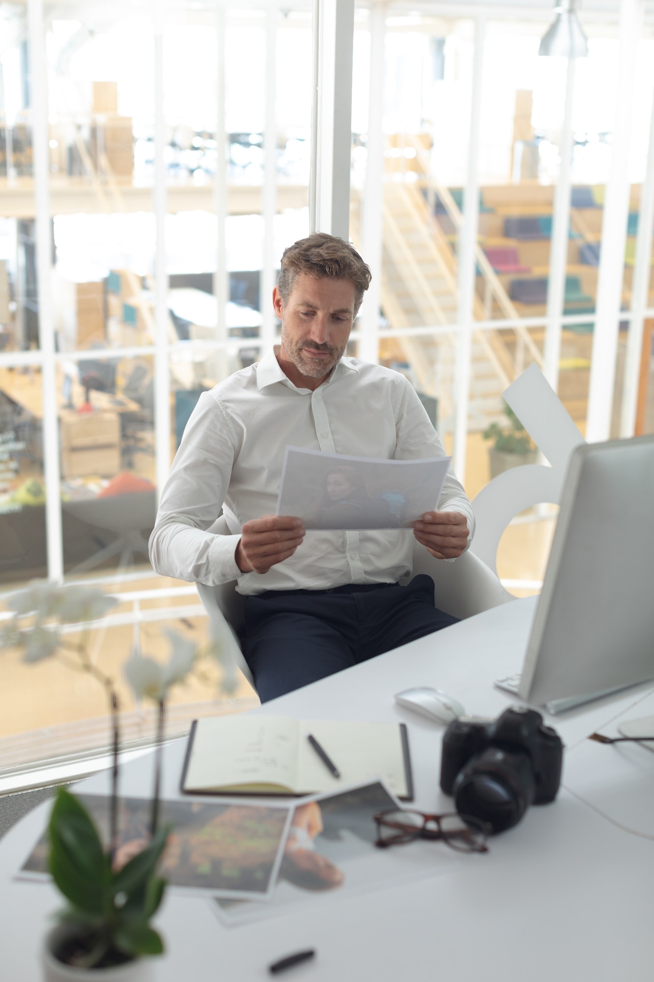 Front view of Caucasian male graphic designer looking at photograph on desk in a modern office